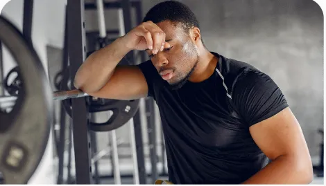 Homem cansado apoiado em um rack de musculação