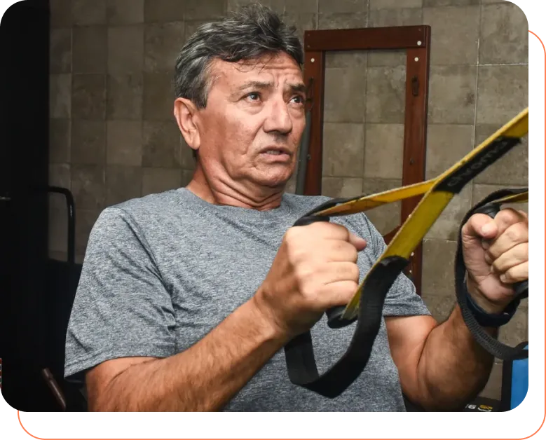 Aluno mais velho treinando no TRX com acompanhamento