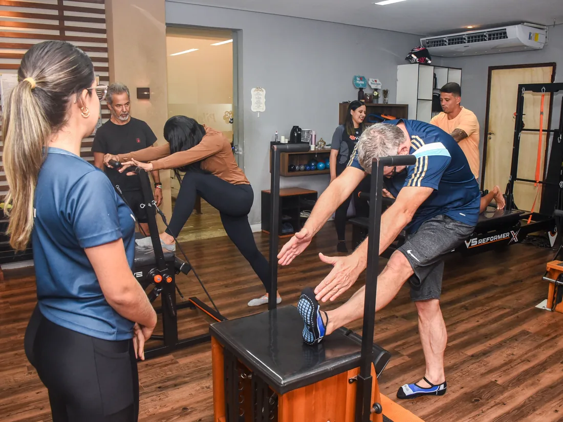 Professora corrigindo a posicao de uma aluna no aparelho de Pilates