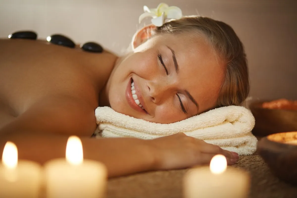 Cliente relaxando em terapia com pedras quentes e velas